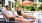 A man and a woman talking to each other on pool lounge chairs